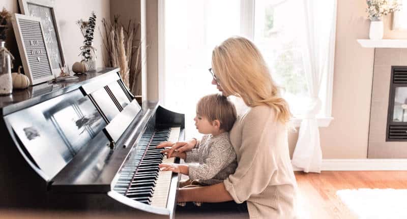 Mum teaching her child to play piano
