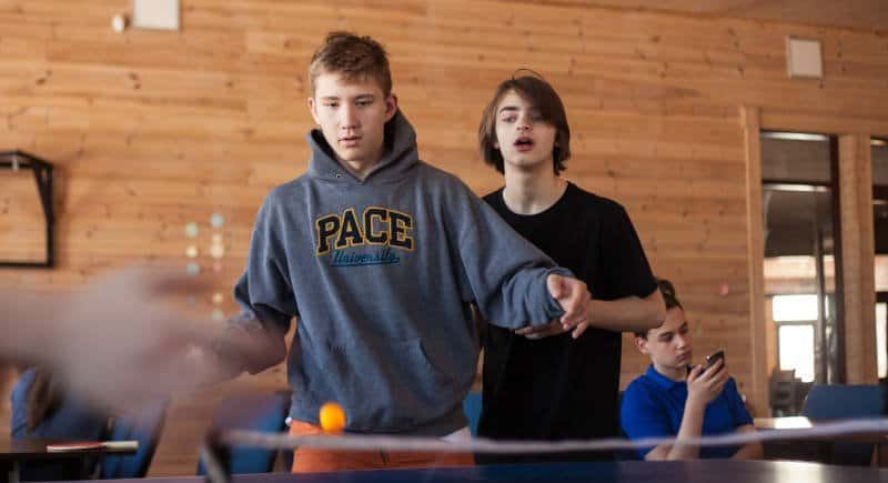 Young guys playing table tennis in game room